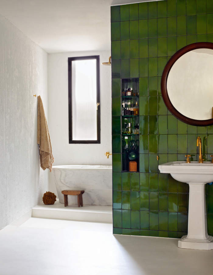 Modern bathroom with green tiles and freestanding tuib