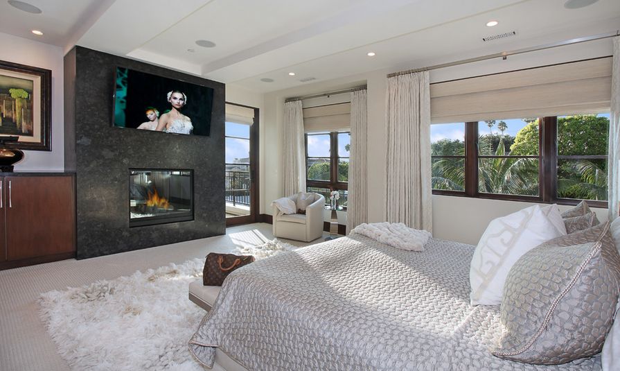 Modern bedroom with fireplace and tv above