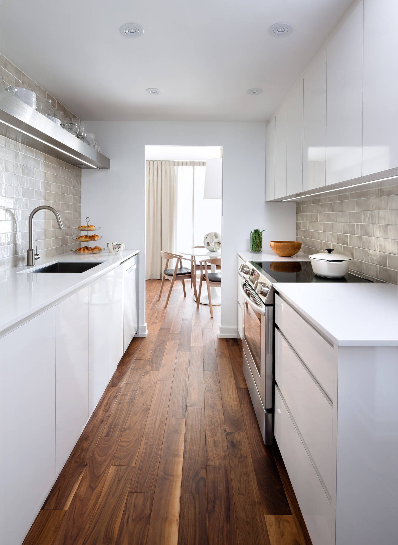 Cream backsplash and white cabinets in a galley kitchen.