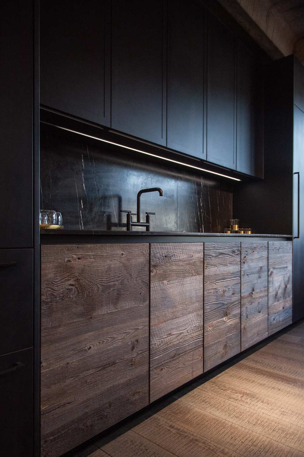 Modern kitchen design featuring black marble and unfinished wood for doors lower cabinets