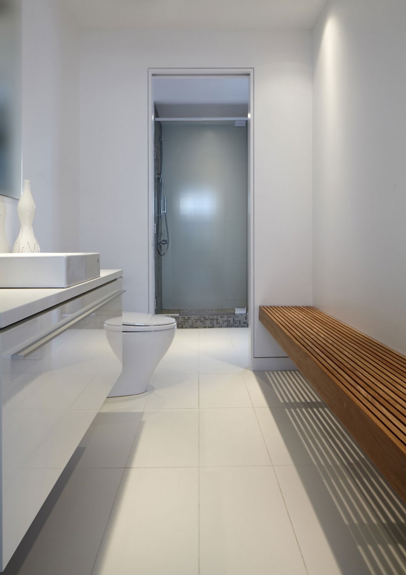 Narrow white bathroom with a wooden bench