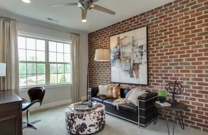 Office room with exposed brick wall and ottoman chowhide in front of a leather sofa