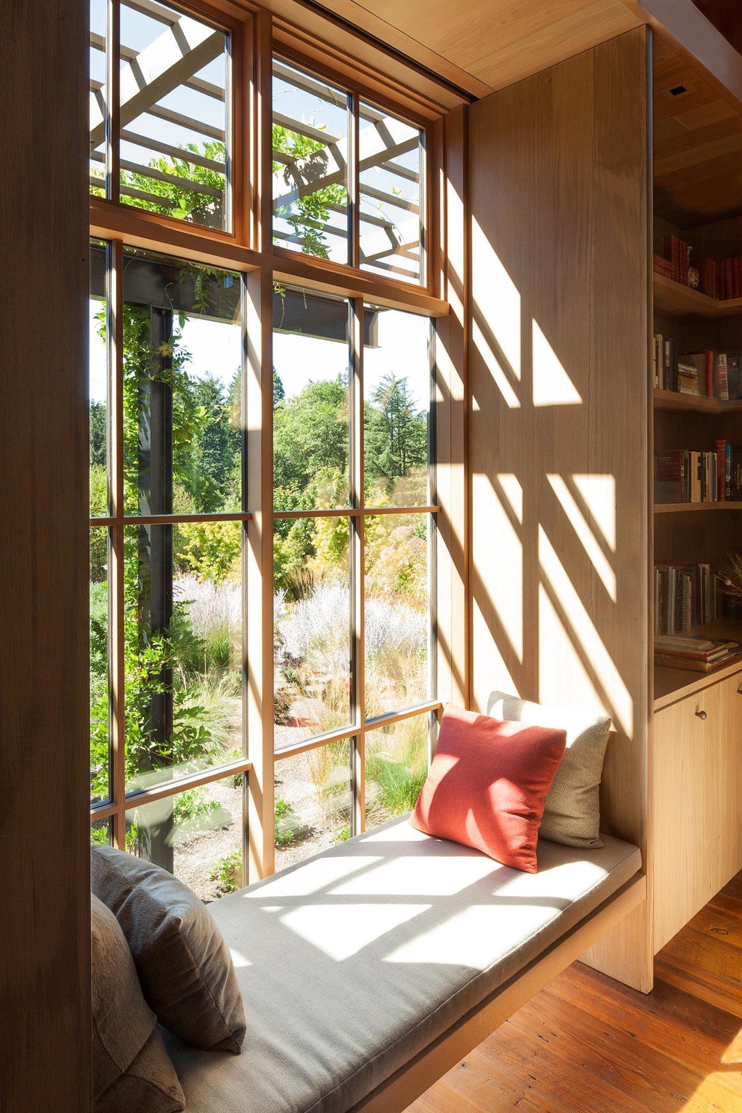 A window seat is a sweet addition to the room, again capitalizing on the garden view.