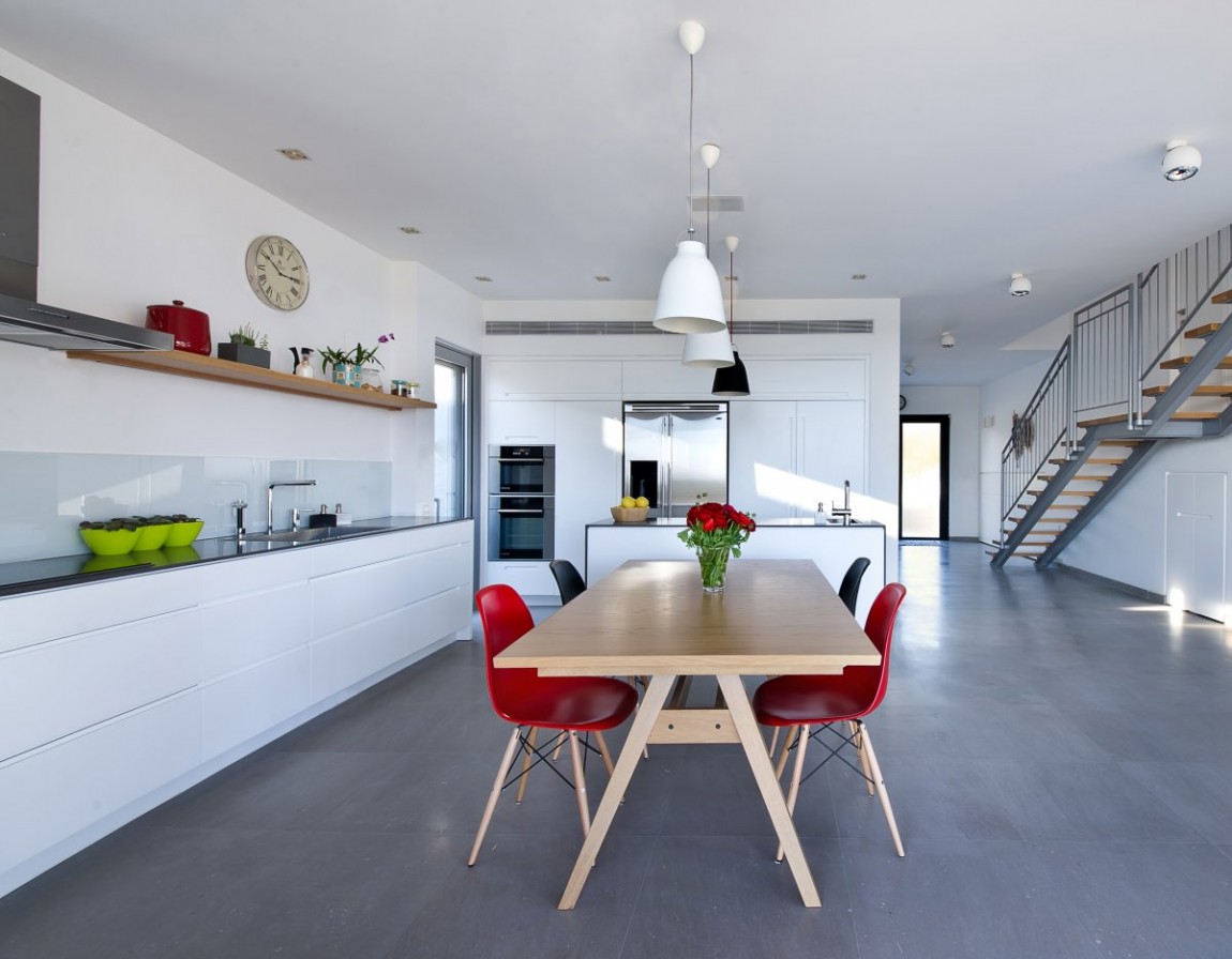 Open space kitchen with white cabinets and polished concrete floor