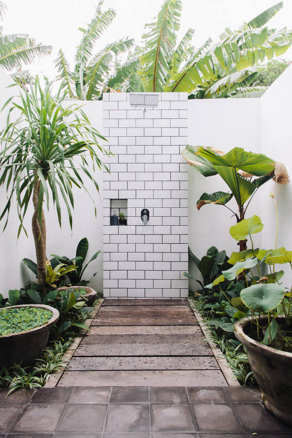 Outdoor shower design with subway tiles and lot of plants