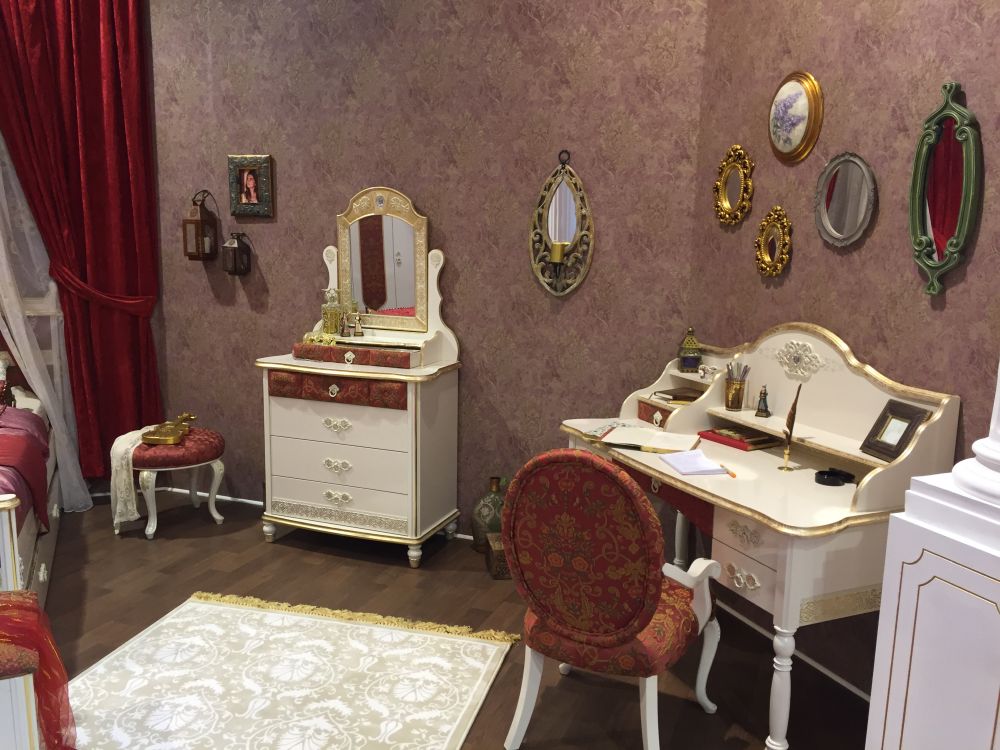 A classic writing desk with a decorative golden rim and soft and delicate curves fits perfectly in a girl's room