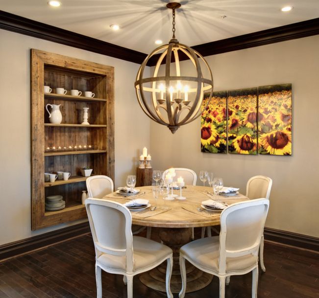 Round dining table and chandelier over it with built in shelves into the walls