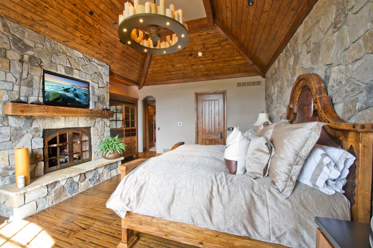 Rustic craftsman bedroom stone fireplace and wood ceiling