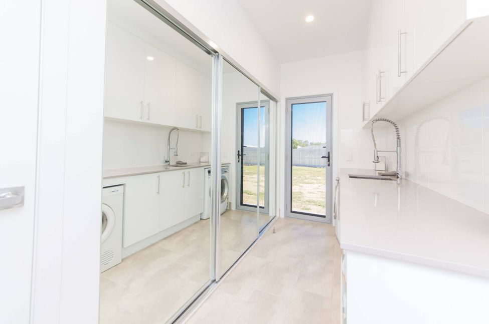 Small and narrow laundry room with sliding doors and mirror over