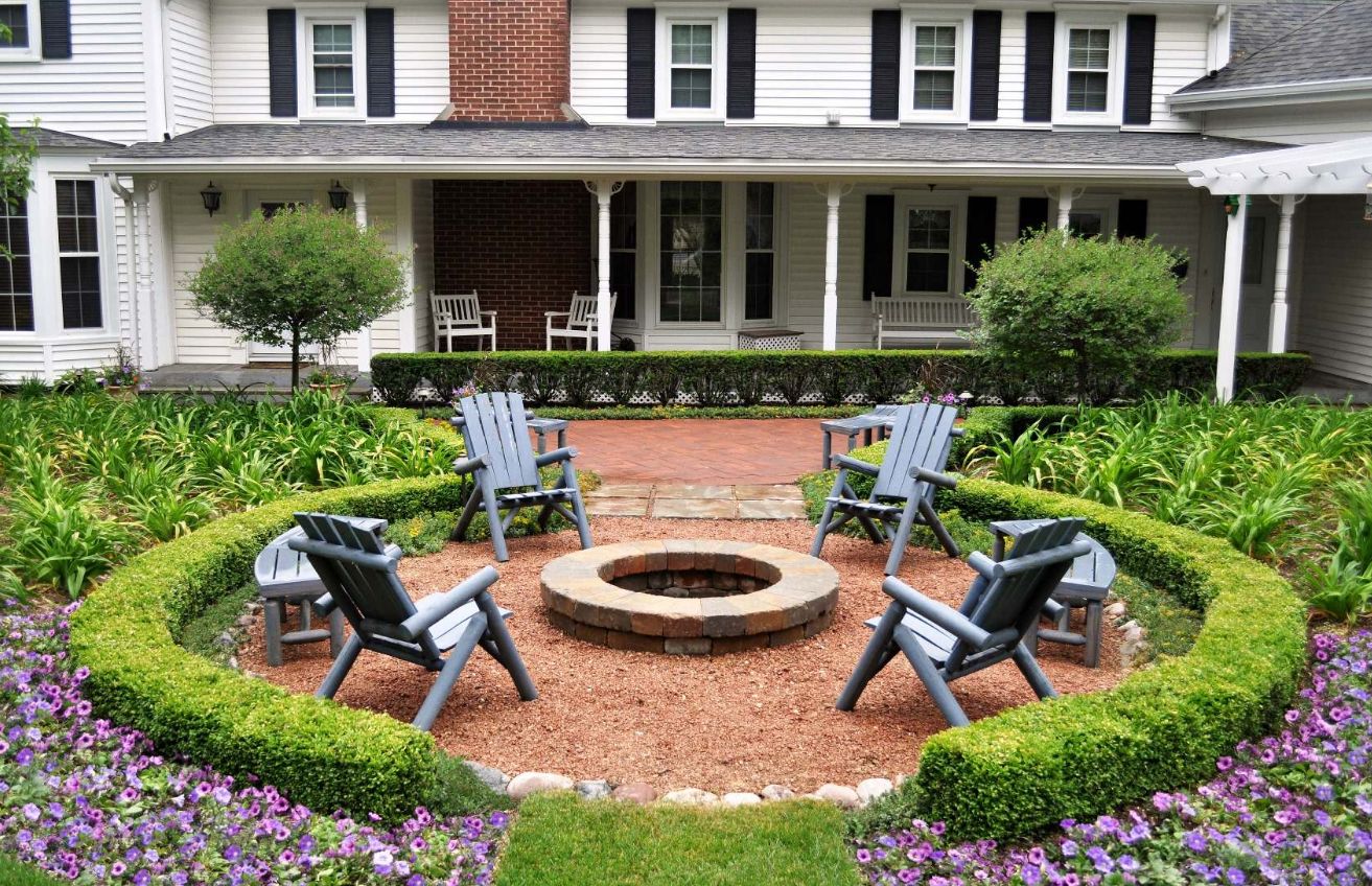 Small brick fire pit in the middle of the garden green small fence