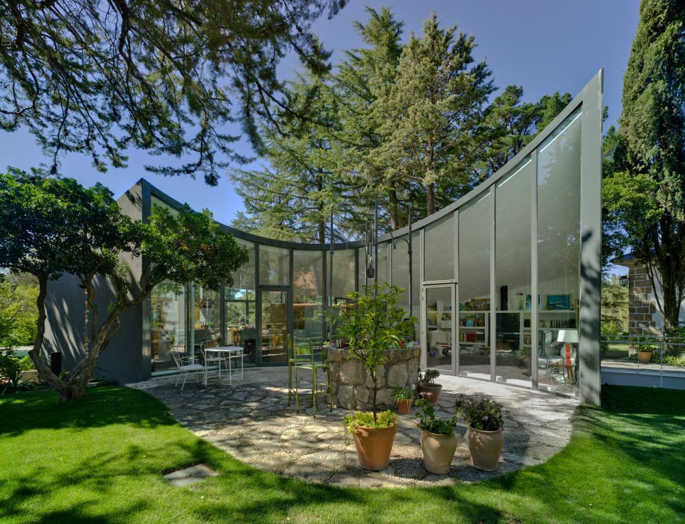 The house is surrounded by vegetation and the full-height windows allow it to bring the outdoors in