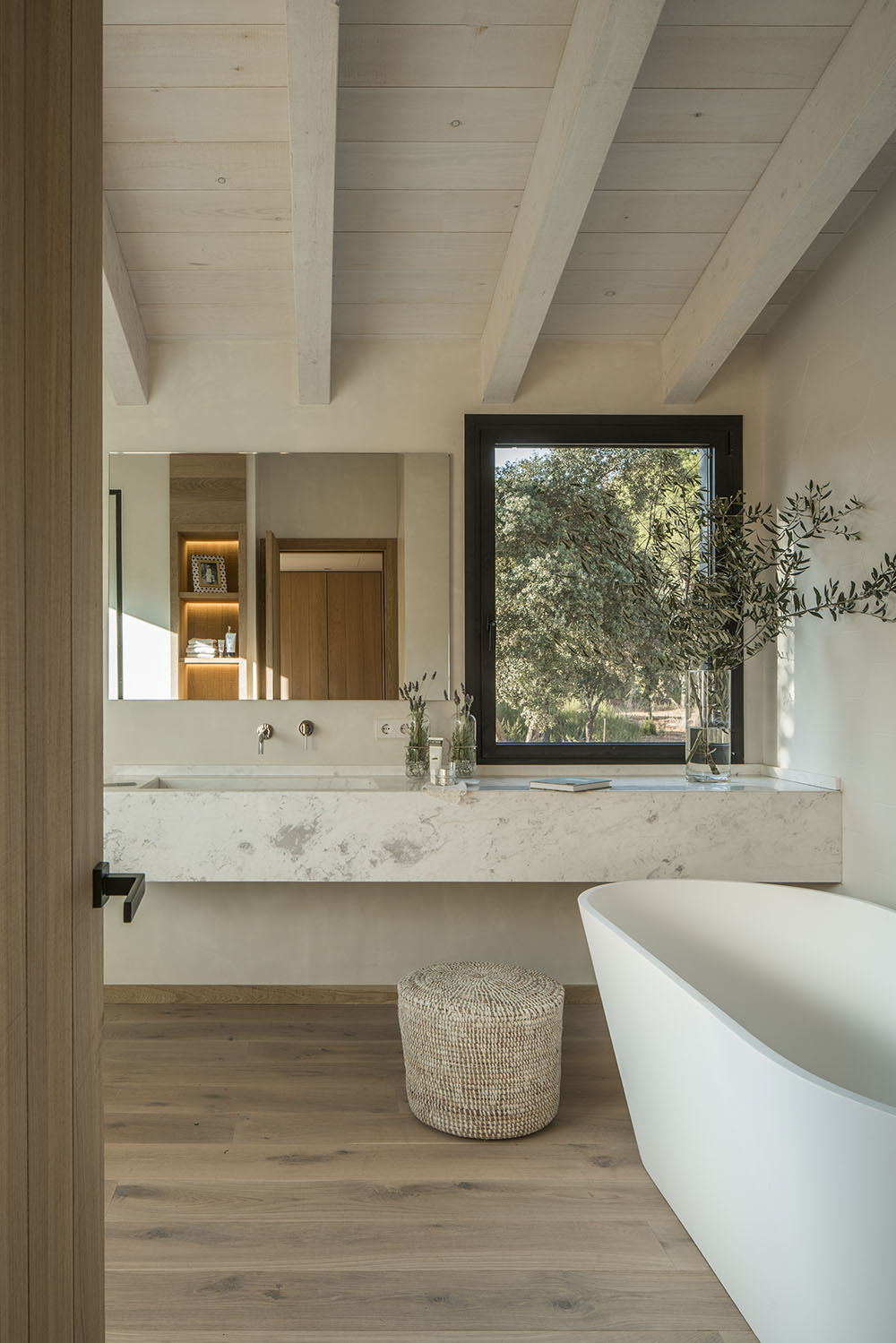 The bathtub affords a view of the olive trees outside.