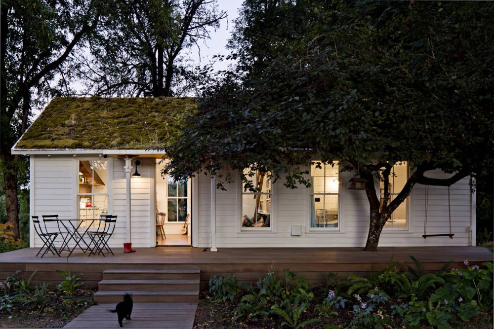 Tiny house with green roof and white exterior