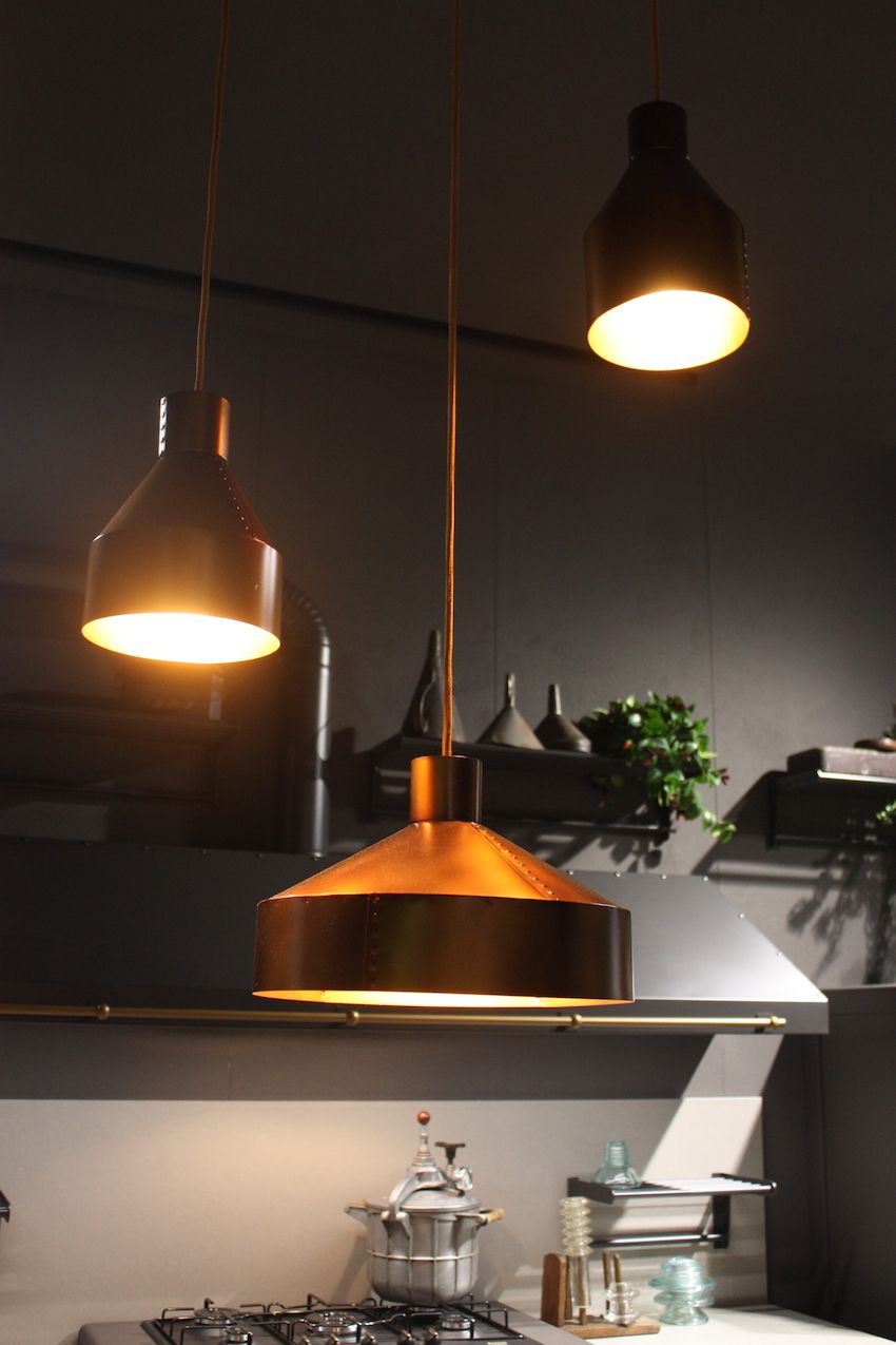 This trio of kitchen pendant lights shown by Ar-Tre demonstrates that they do not need to be the same size or be  hung at the same height. The rustic, riveted copper pendants are different sizes, with the largest placed closest to the work surface for good illumination.