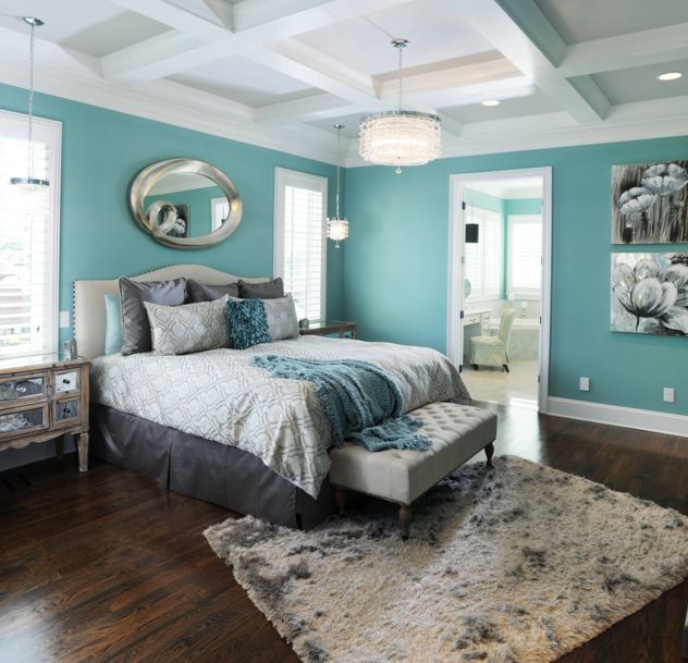 Turquoise bedroom with a round mirror above bed