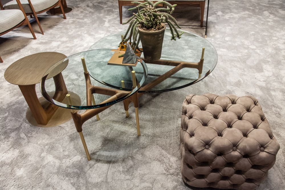 The Joint coffee table features a base made of brass and canaletta walnut and a tempered glass top