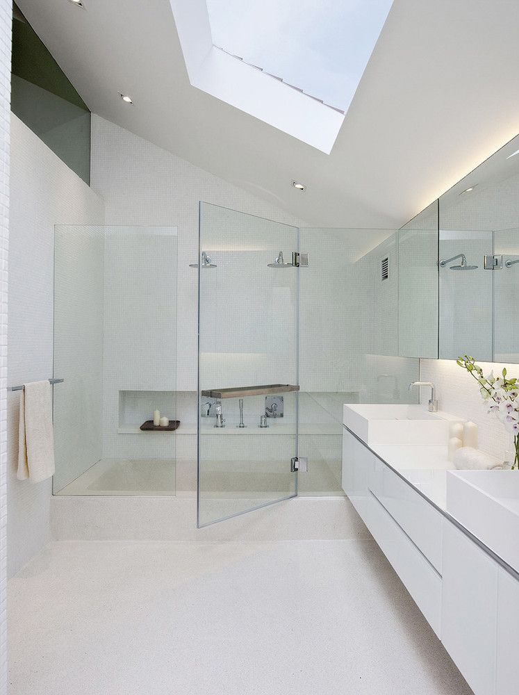 White bathroom with glass shower doors and sky lighting