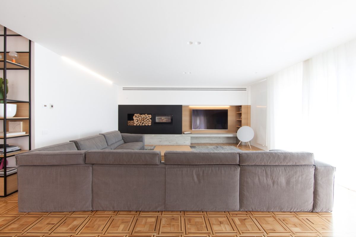 White contemporary living room with tv on the wall and firewood storage