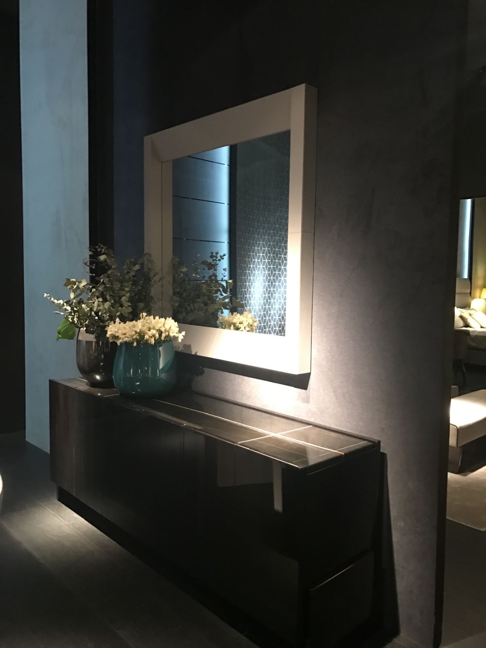 White framed entryway mirror and sideboard with flowers on top