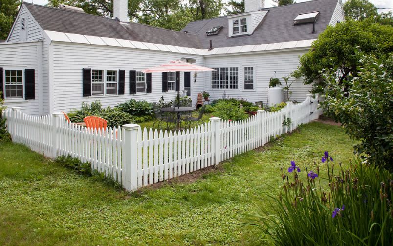 White house beadboard with window shutters and white picket fence