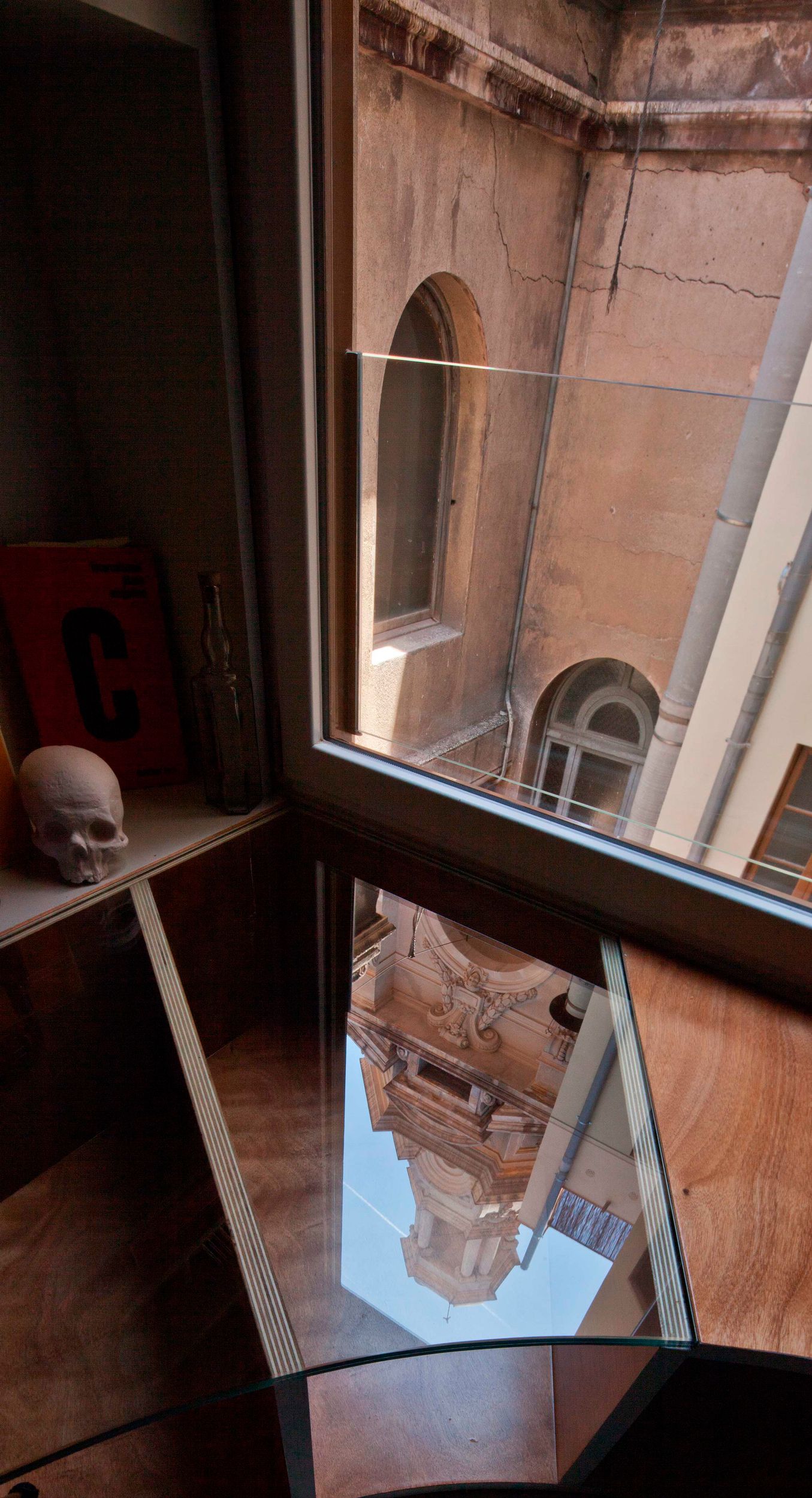 The view out the window in the corner is artfully reflected in the glass sections of the shelving.