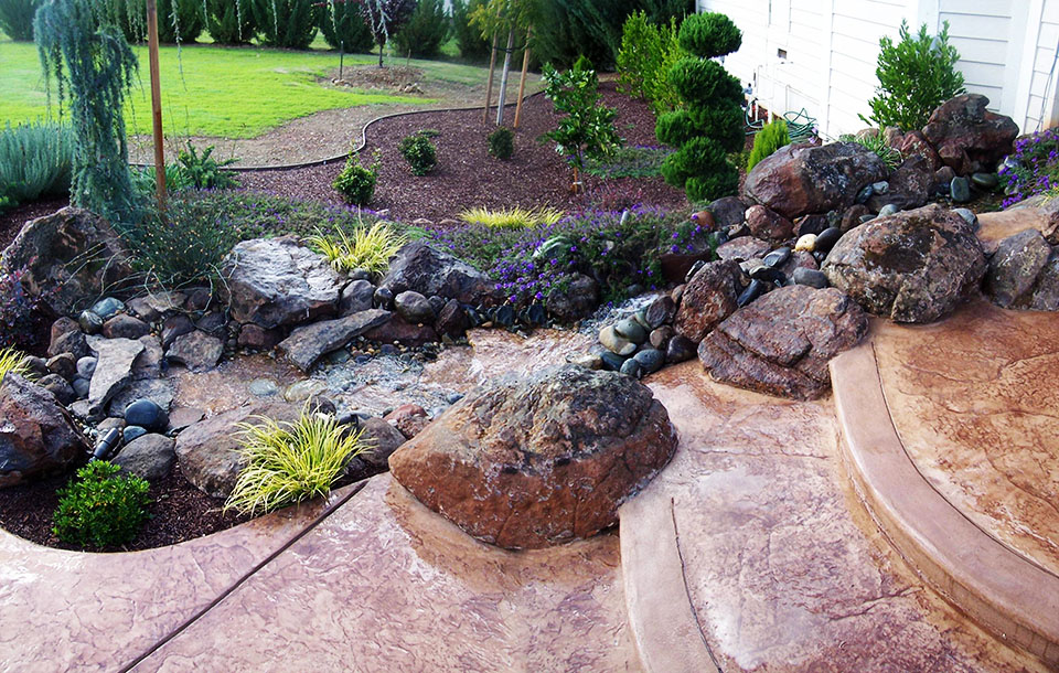 Backyard rock stream water feature stamped concrete stone steps