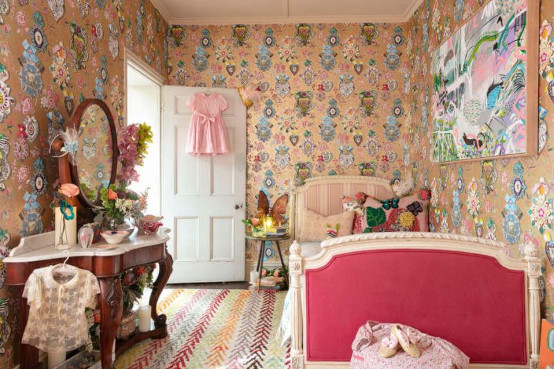 Childrens room with flowered wallpaper and a pink bed