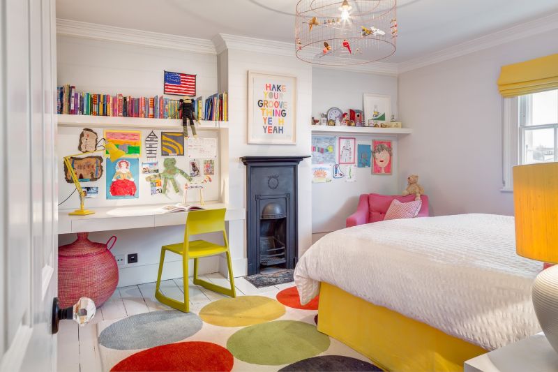 Childrens room with writing desk and bookshelf above and fireplace