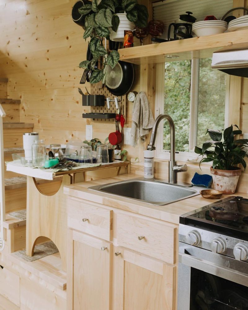 The kitchen is small but well-equipped, with storage shelves and a window in front of the sink