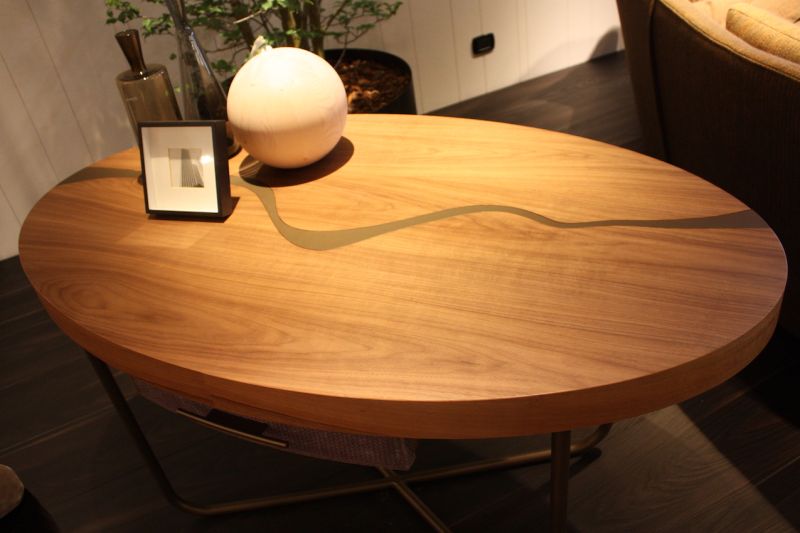 A thick wood coffee table top is made light with a modern metal base from Il Loft. The sinuous inlaid wave adds interest and keeps the table from feeling too hefty.