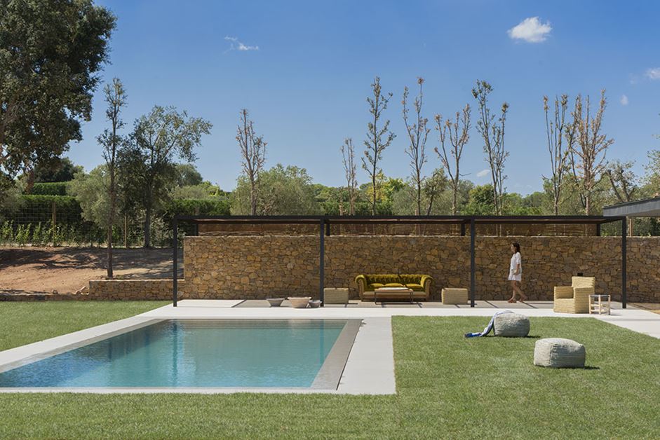 A stone wall provides privacy for the pool from the side and an overhang gives shade.