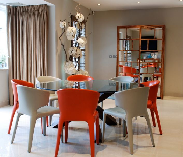 round glass dining table with colorful chairs