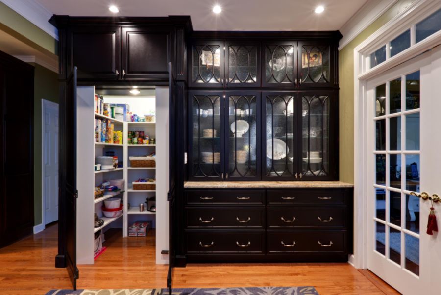 Traditional kitchen pantry idea in Atlanta with glass front cabinets and black cabinets