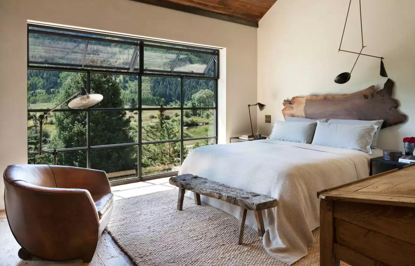 Master bedroom with large windows leather armchair and live edge headboard