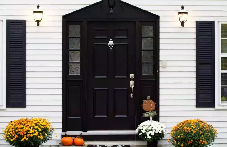 White exterior with black front house and fall poted flowers