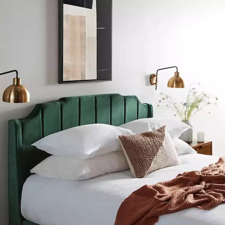 green bed and golden lamps on the wall