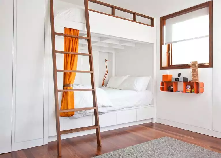 White bunk beds with orange curtain and ladder